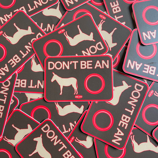 A collection of rectangular black stickers with red and white text and graphics, one of which shows a silhouette of a donkey, and the phrase 'DON'T BE AN'.