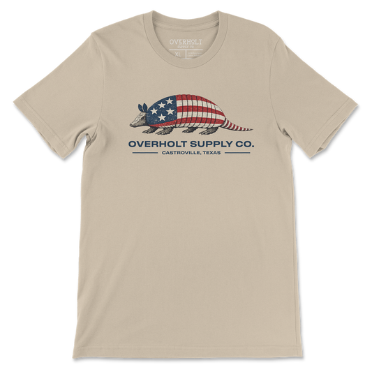 Americana armadillo graphic t-shirt on soft cream Bella and Canvas tee by Overholt Supply Co. featuring red, white, and blue design