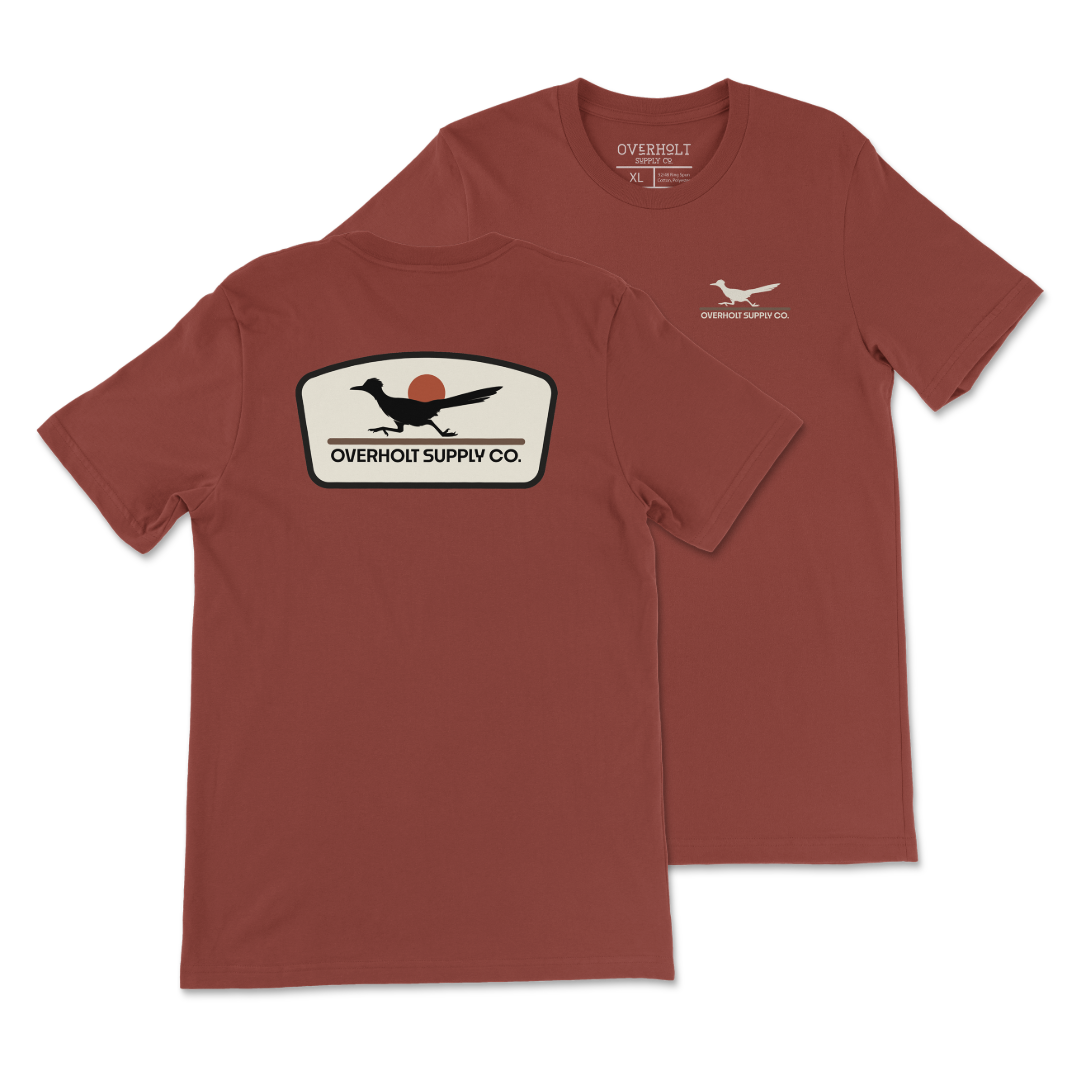 Rust Bella and Canvas T-shirt with a small cream OSC Roadrunner chest print and a large cream, black and rust Roadrunner badge on the back.
