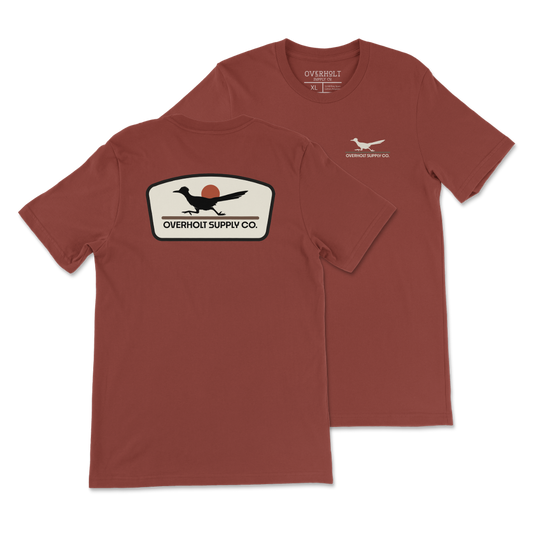 Rust Bella and Canvas T-shirt with a small cream OSC Roadrunner chest print and a large cream, black and rust Roadrunner badge on the back.