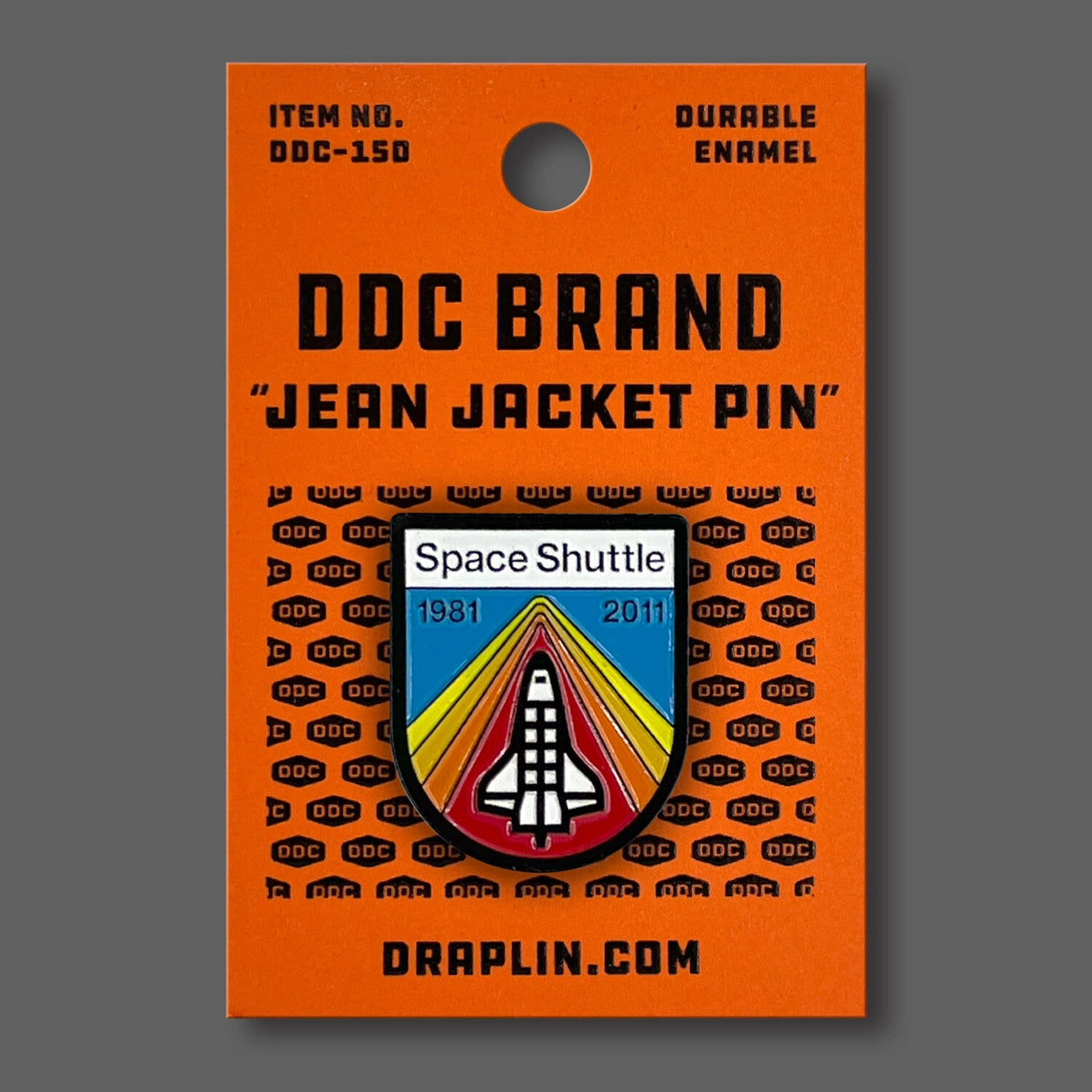 Draplin Design Company space shuttle enamel pin featuring 1981 to 2011 commemorative design on orange backing card
