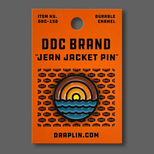 Draplin Design Company Waves enamel pin featuring sunset and ocean design on orange backing card