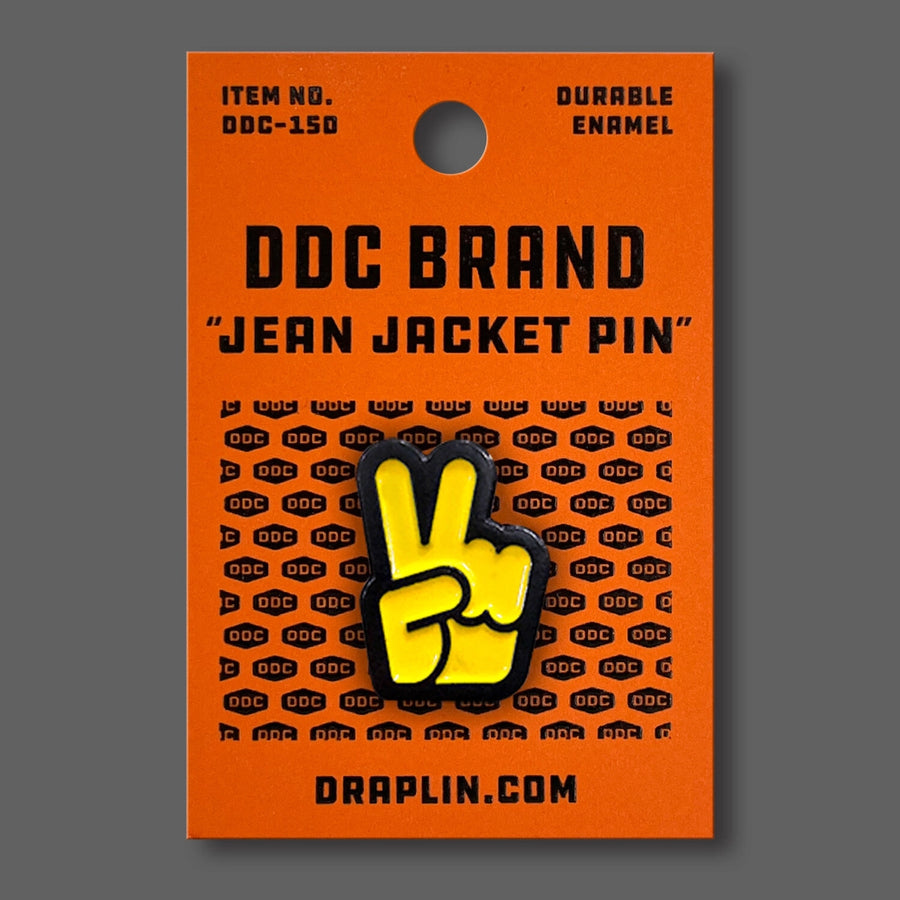 Draplin Design Company yellow peace fingers enamel pin on orange backing card