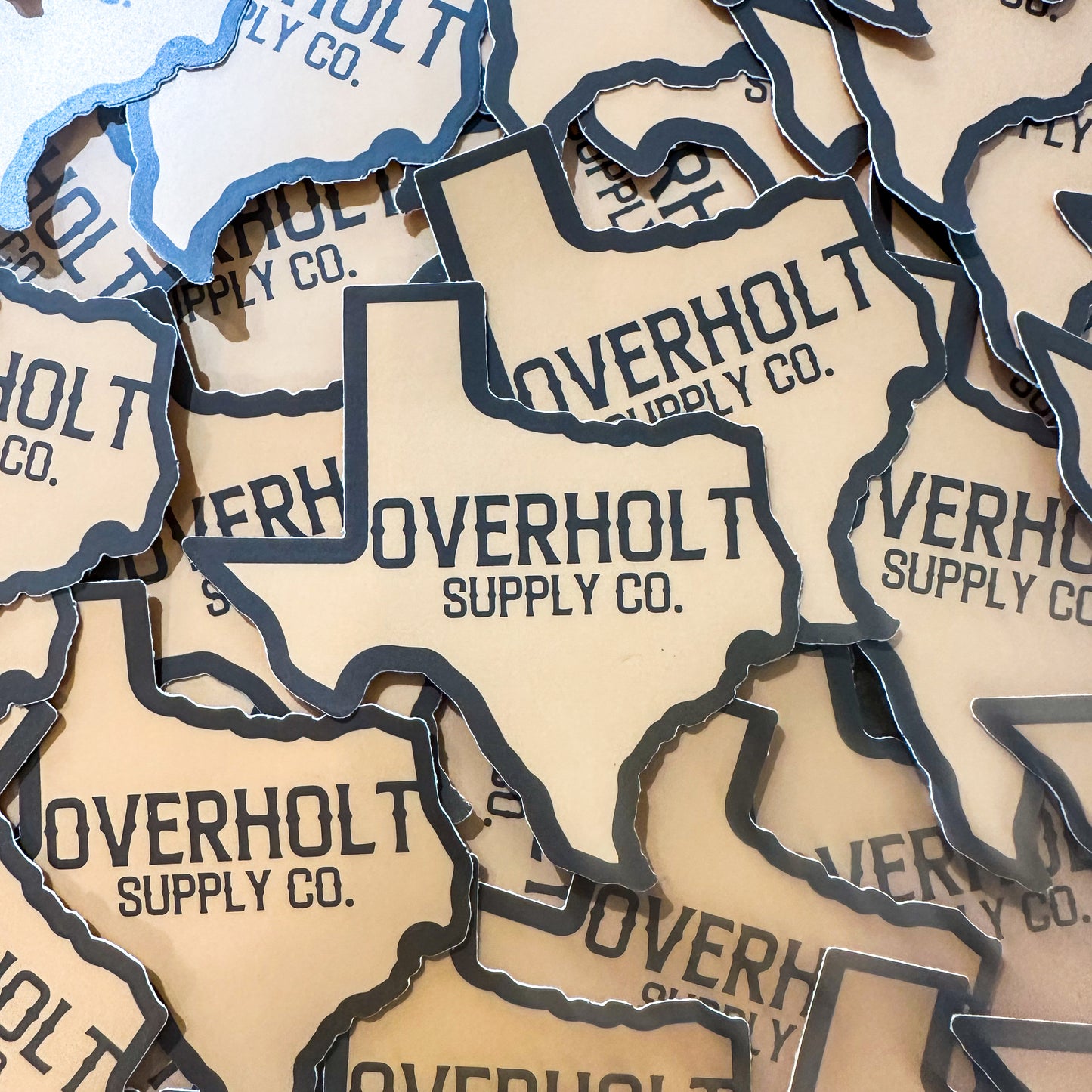 A collection of stickers on top of each other in the shape of Texas with Overholt Supply Co. in the middle