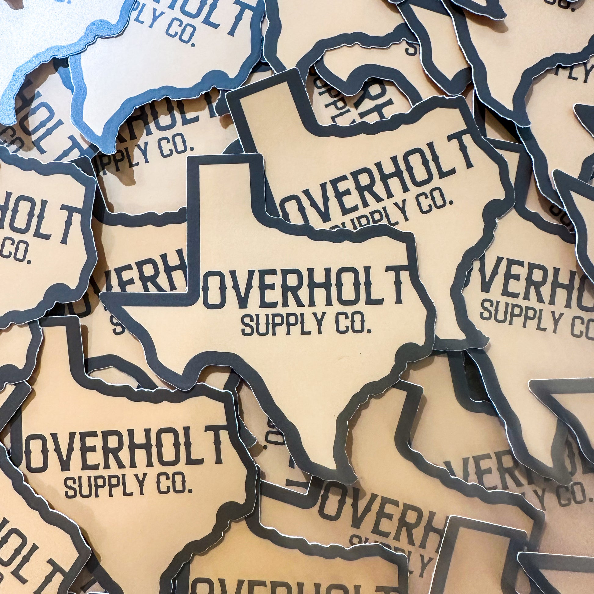 A collection of stickers on top of each other in the shape of Texas with Overholt Supply Co. in the middle