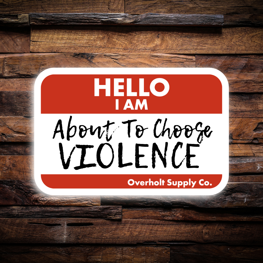 Name tag with text 'HELLO I AM About To Choose VIOLENCE' on a wooden background